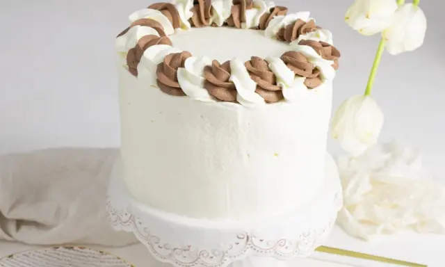 Tarta blanca con borde de nata y chocolate, lista para celebrar.