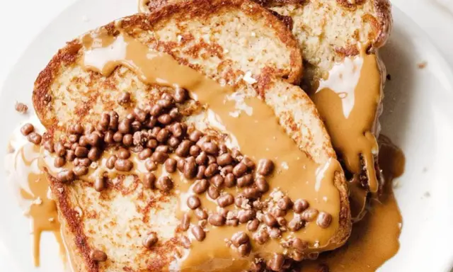 Tostadas francesas cubiertas con crema de cacahuete y crujientes bolitas de chocolate. Un desayuno delicioso y tentador.