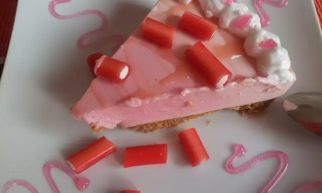 Deliciosa tarta de regaliz rojo con crema rosa y adornos de regaliz.