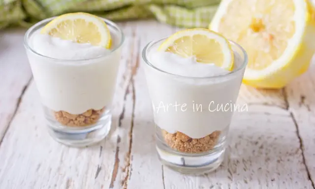 Dos vasitos de mousse de limón con base de galleta y rodaja de limón encima.