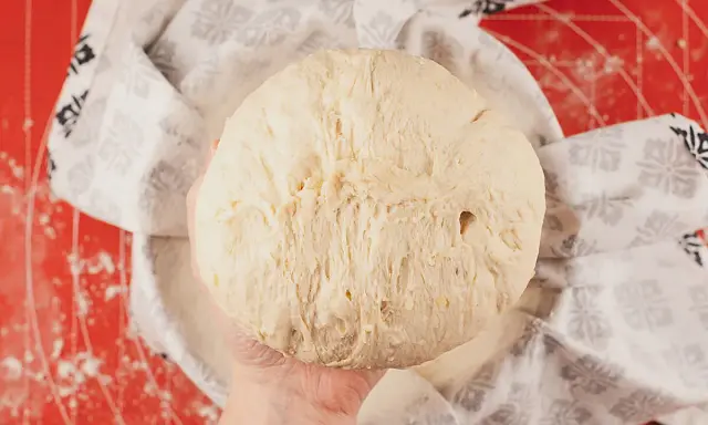 Masa de pan de patata esponjosa, lista para hornear, cubierta con un paño decorado.