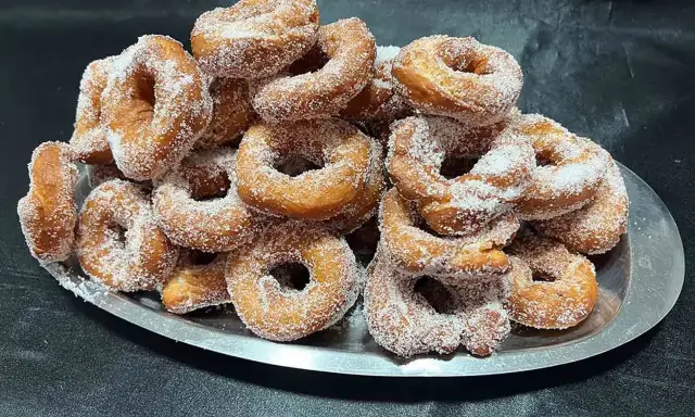 Montón de buñuelos de cuaresma espolvoreados con azúcar, listos para disfrutar.