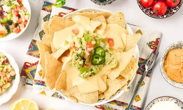 Nachos con queso cubiertos de guacamole y pico de gallo, listos para disfrutar.