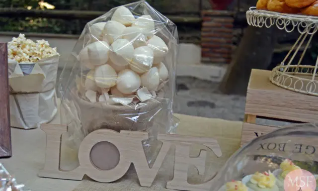 Mesa dulce con palomitas, merengues, cupcakes y letras de madera "LOVE".
