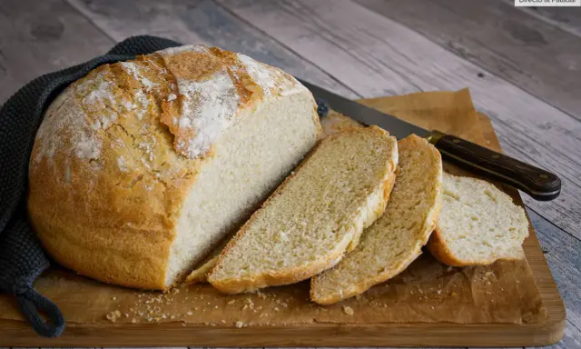 Un delicioso pan casero con levadura fresca, recién horneado y cortado en rebanadas sobre una tabla de madera.