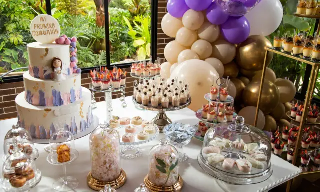 Mesa dulce para comunión con pastel, postres individuales, dulces y globos.