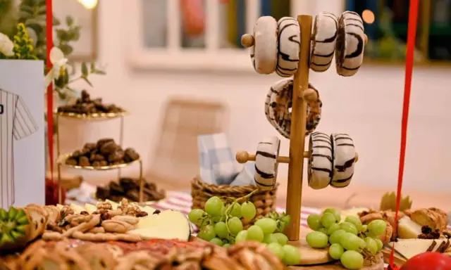 Deliciosa merienda de cumpleaños para adultos: donuts, quesos, frutos secos y uvas.