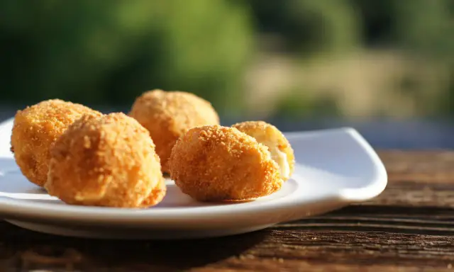 Croquetas caseras doradas y crujientes en un plato blanco, listas para disfrutar.
