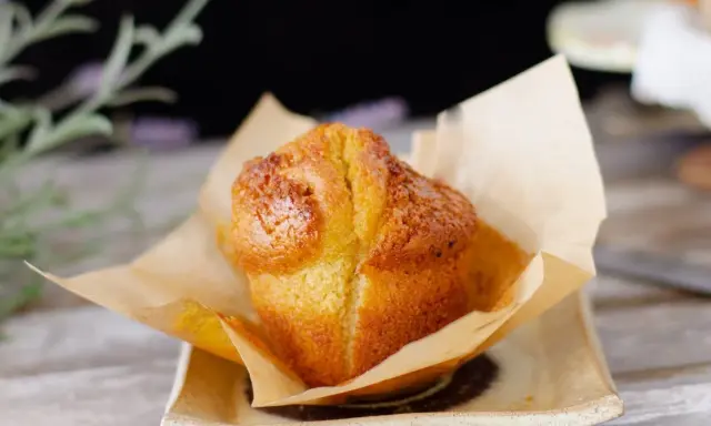 Un muffin dorado, recién horneado, envuelto en papel de horno. Perfecto para acompañar tu proceso de hacer masa madre.