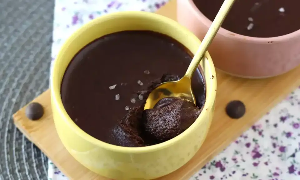 Delicioso mousse de chocolate en un cuenco amarillo, con una cuchara dorada lista para probarlo. ¡Un placer para los sentidos!