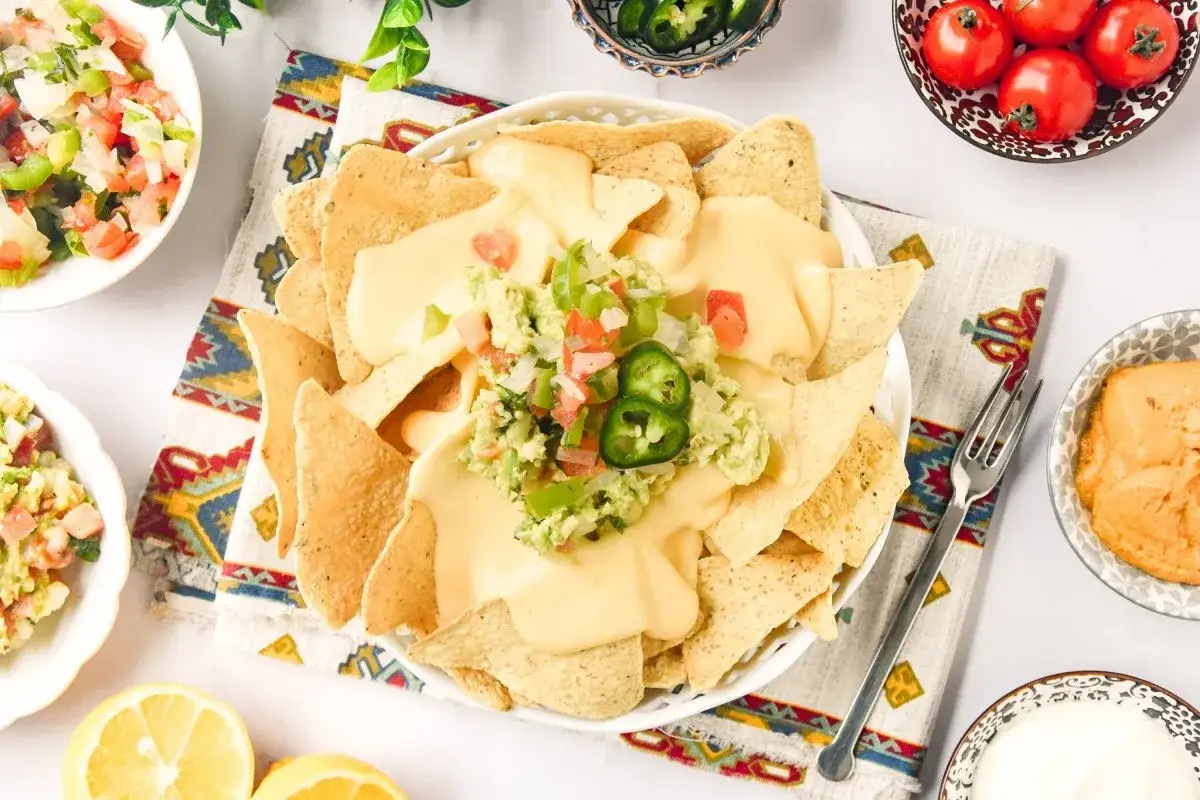 Nachos con queso cubiertos de guacamole y pico de gallo, listos para disfrutar.