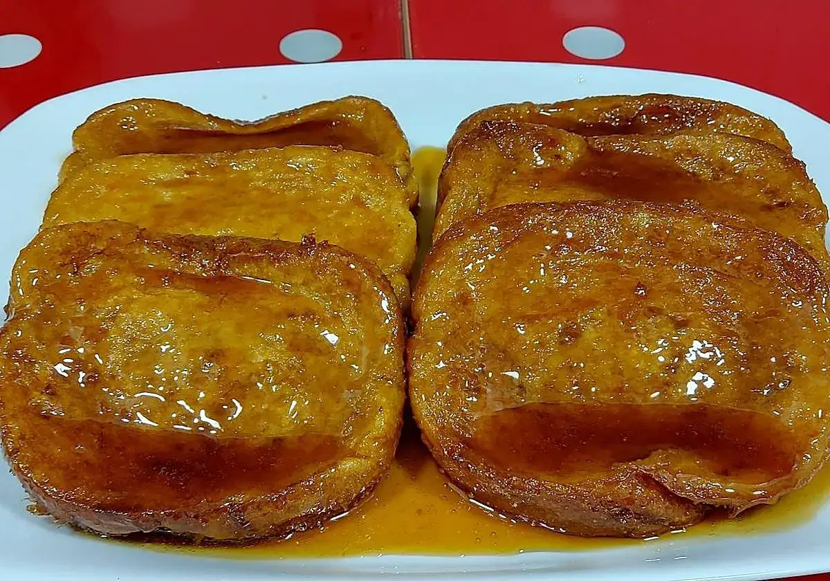 Torrijas de vino doradas y jugosas, cubiertas de un almíbar brillante, listas para disfrutar.