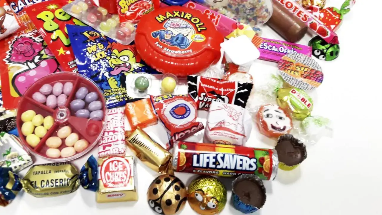Un surtido de chuches años 60: caramelos, chicles y chocolates con envoltorios coloridos y divertidos.