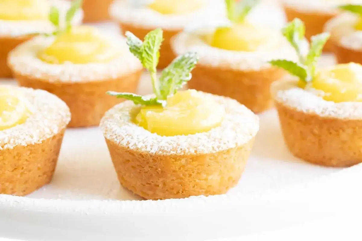 Deliciosos pastelitos con relleno de lemon curd, espolvoreados con azúcar glas y decorados con hojas de menta.