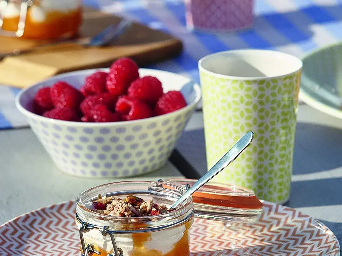 Deliciosos postres para picnic: yogur con granola y frambuesas frescas, listos para disfrutar al aire libre.