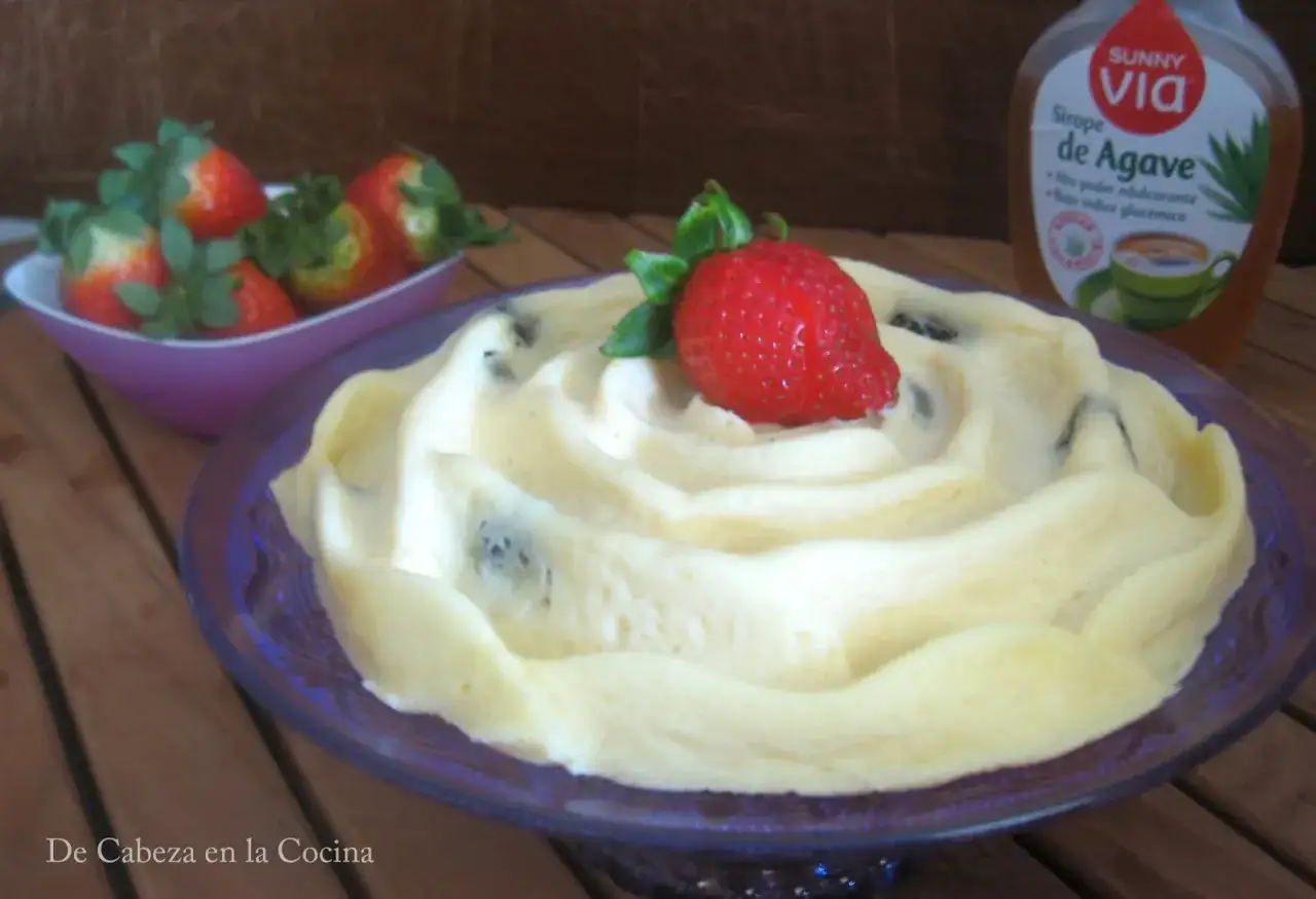 Postre cremoso con fresas y una botella de sirope de agave.