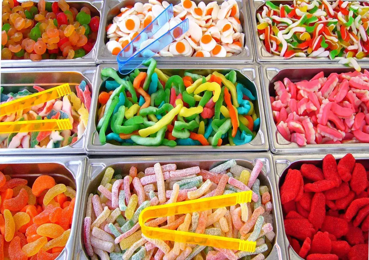 Bandejas llenas de chuches típicas de España: gusanos, dientes, gominolas de frutas y más. ¡Un festín de colores y sabores!