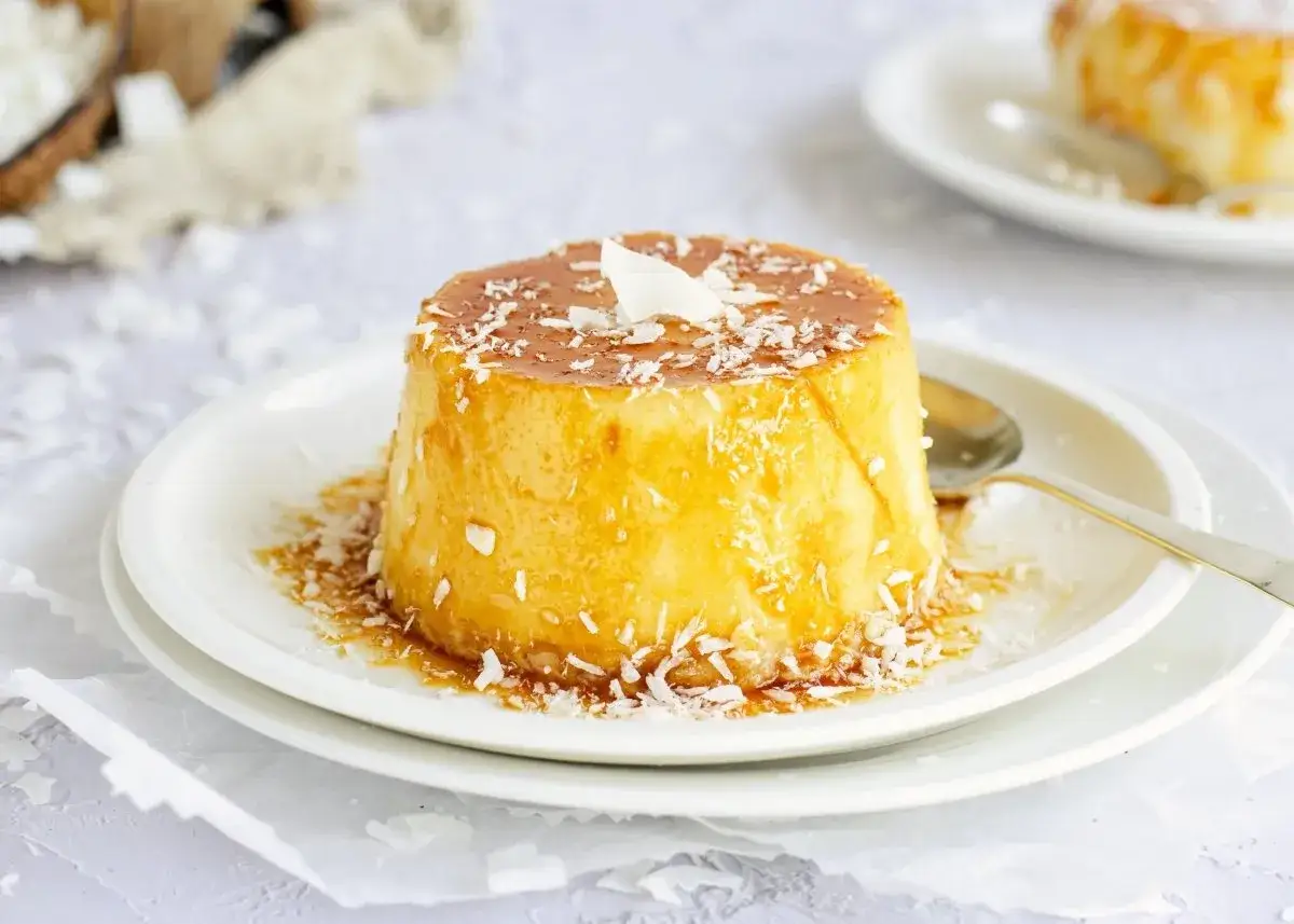 Delicioso flan de coco con caramelo líquido y coco rallado, servido en un plato blanco.