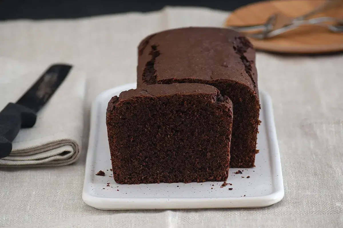 Una rebanada de deliciosa coca de chocolate, esponjosa y oscura, lista para disfrutar.