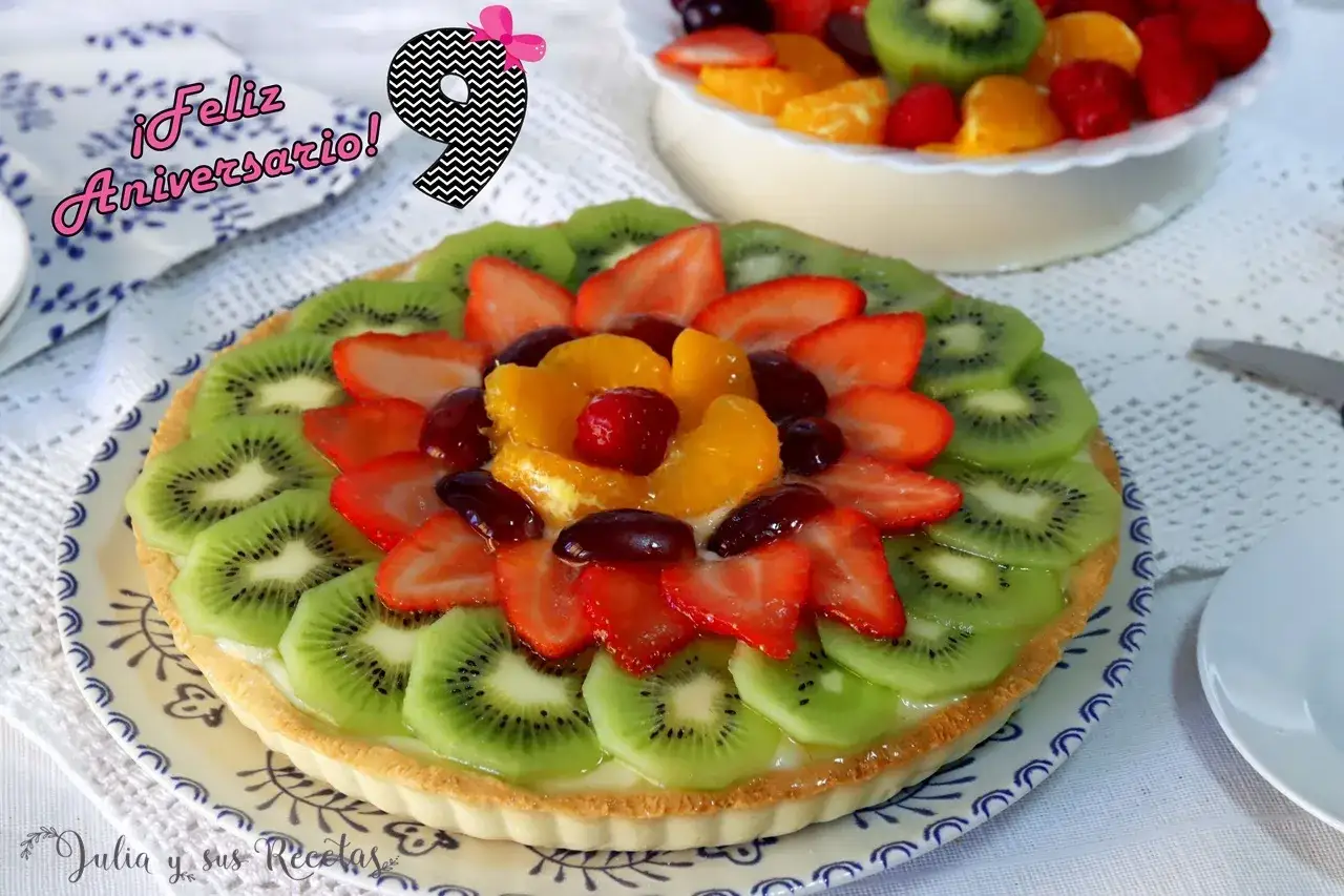 Deliciosa tarta con decoración de tartas con frutas: kiwi, fresas, naranjas y uvas. ¡Feliz aniversario!