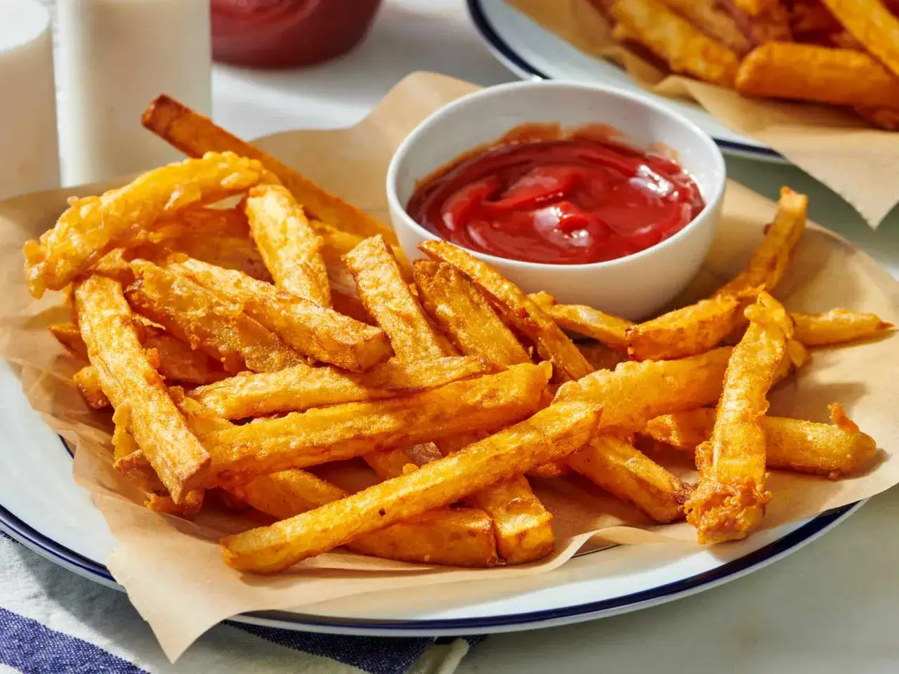 Un plato rebosante de patatas fritas doradas y crujientes, con un cuenco de ketchup rojo brillante. ¡Perfectas para mojar!