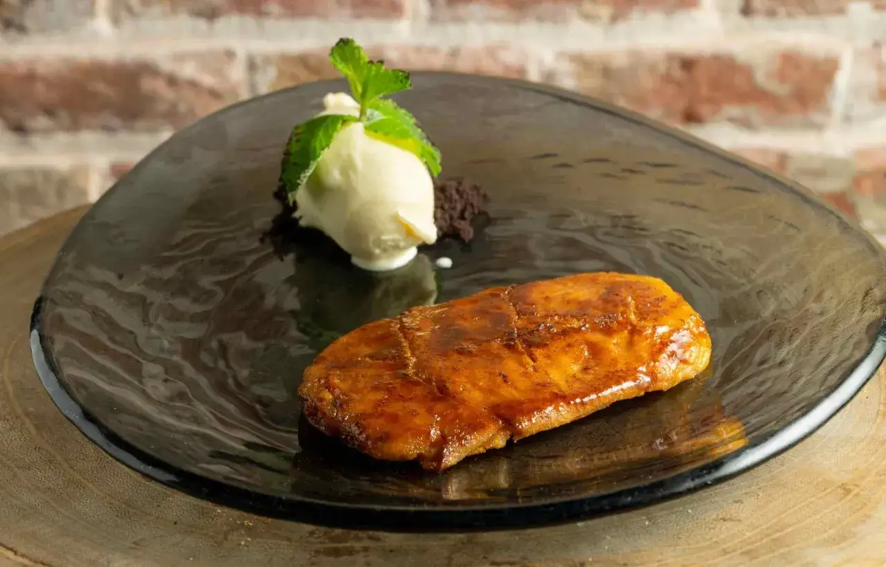 Deliciosa torrija de vino, dorada y caramelizada, acompañada de helado de vainilla y menta fresca.