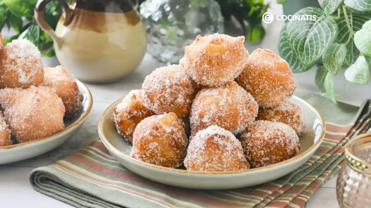 Montón de buñuelos de manzana dorados y espolvoreados con azúcar, listos para disfrutar.