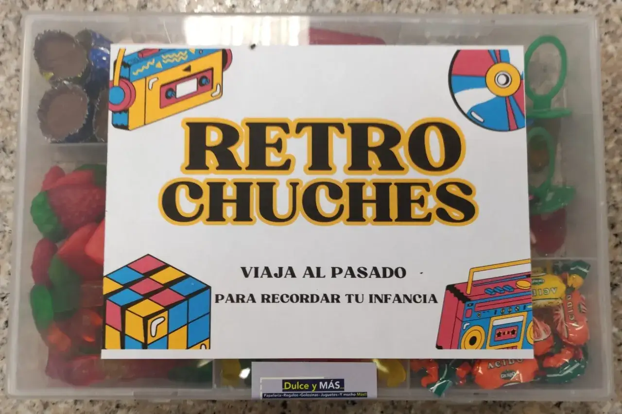 Caja transparente llena de dulces de los 80 que ya no existen, con imágenes de un casete, un cubo de Rubik y un radiocasete.