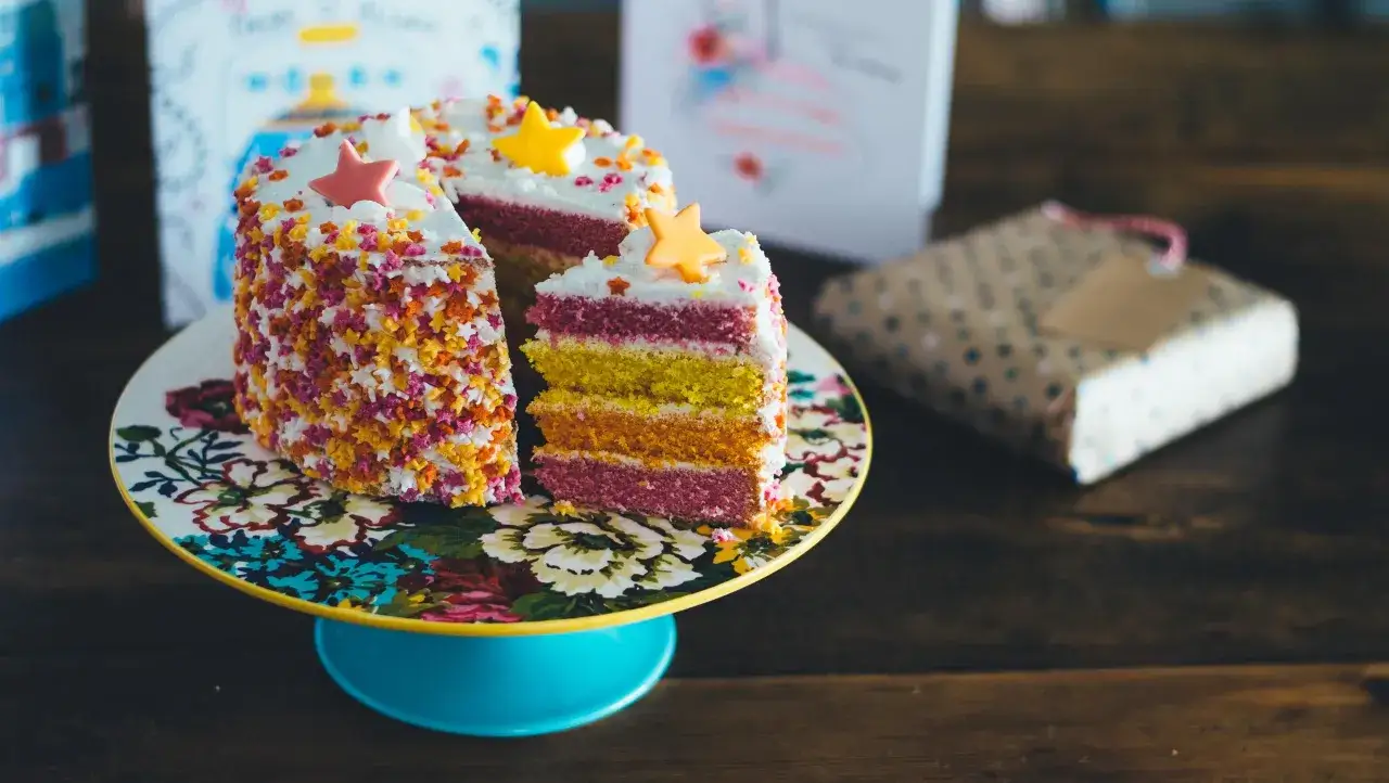 Pastel de capas arcoíris con chispas de estrellas y estrellas de fondant. ¡Ideas para decorar tartas que inspiran alegría!