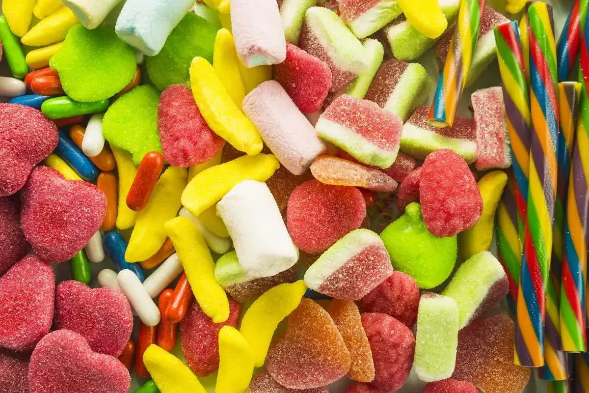 Un surtido vibrante de dulces celiacos: gomitas de frutas, malvaviscos y bastones de caramelo arcoíris.