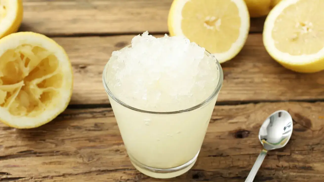 Refrescante granizado de limón thermomix, perfecto para un día caluroso. Limones frescos y una cuchara lista para disfrutar.