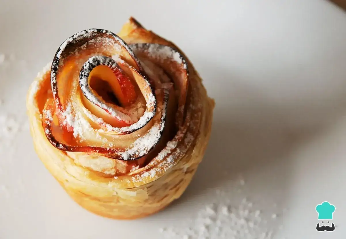 Delicioso postre con hojaldre y manzana en forma de rosa, espolvoreado con azúcar glas.