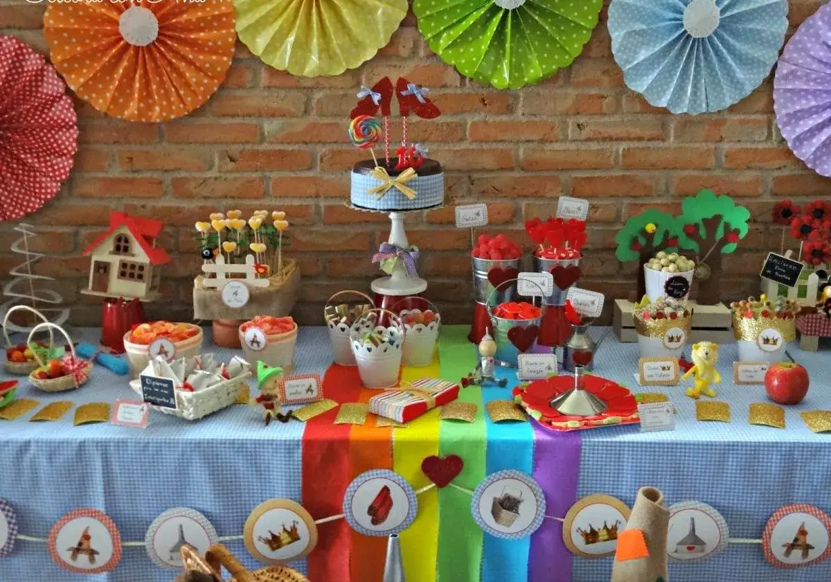 Una mesa dulce casera llena de color y fantasía, con dulces, caramelos y un pastel decorado.