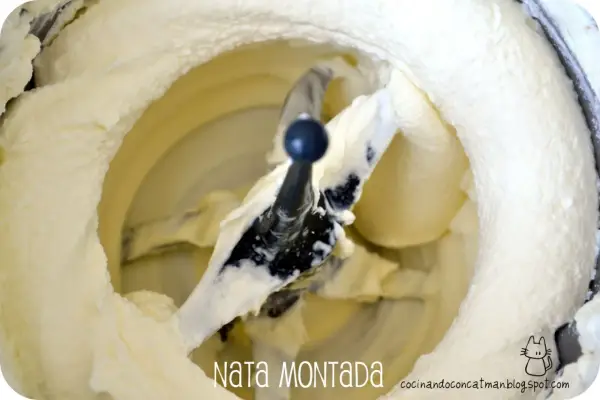 Batidora con pala mezclando nata montada, creando una textura esponjosa y cremosa, lista para postres.